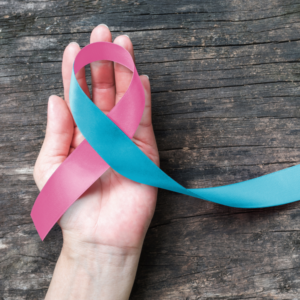 Pink and blue baby loss awareness ribbon held in a hand, symbolising remembrance and support after baby loss