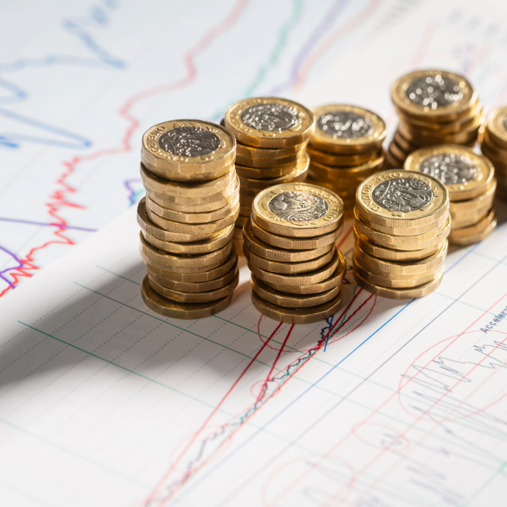 Stacks of one-pound coins on top of financial graphs, representing the economic cost of baby loss in the UK