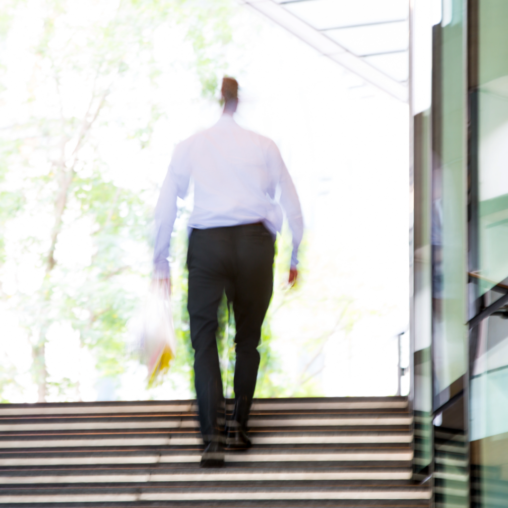 Blurred image of a man walking up stairs in work clothes, symbolising silent struggles and social expectations placed on men after baby loss
