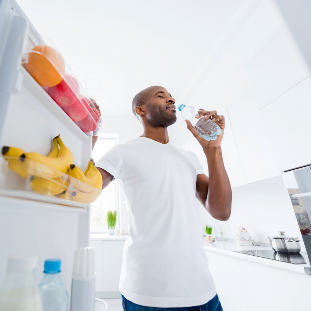 Man drinking water in a bright kitchen, choosing healthy habits after baby loss