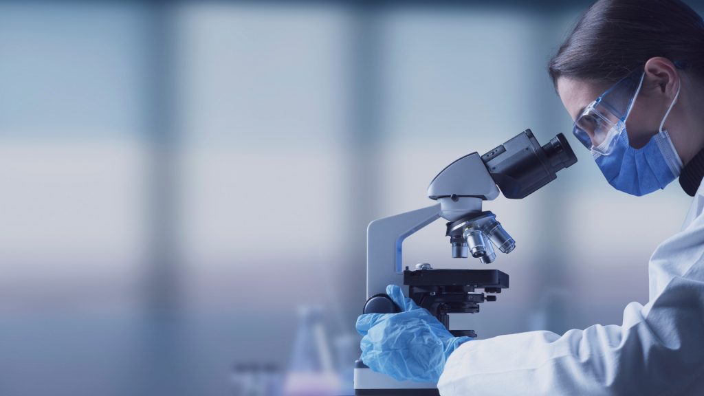 Scientist using a microscope in a lab, representing research into miscarriage rates and baby loss statistics.