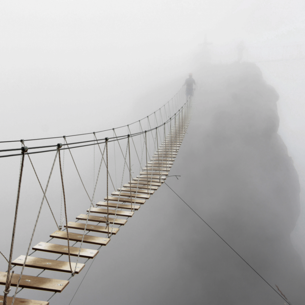 Person crossing a rope bridge into mist, rebuilding confidence and moving forwards after baby loss