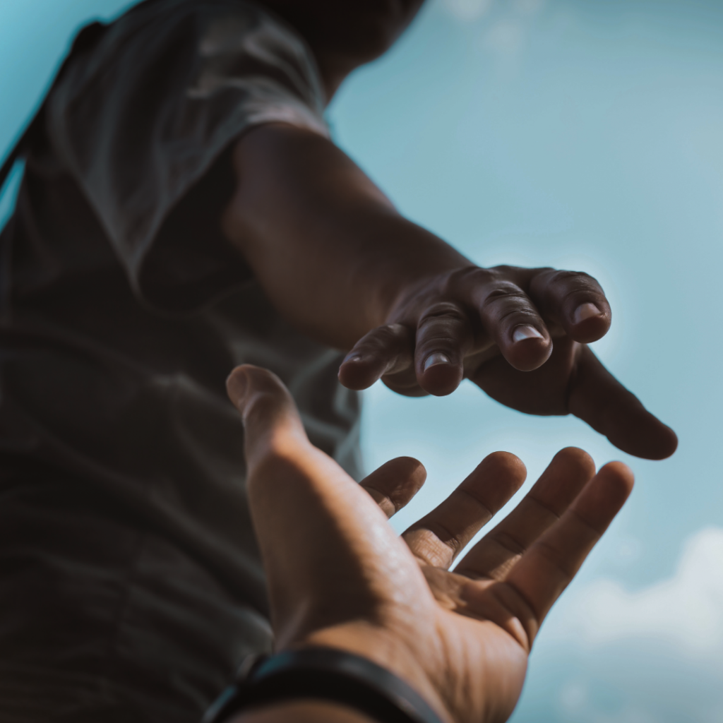 One person reaching down to help another, symbolising how men can take action after baby loss.